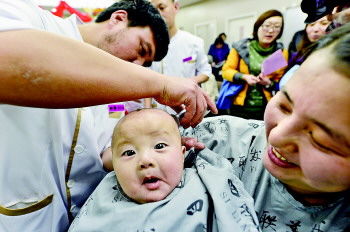 3月13日,一位母亲怀抱孩子到北京王府井四联美发给孩子剃头。当日是农历二月初二,中国民间有“二月二,龙抬头”的说法。在这一天,家长带着孩子到理发店理发,为新的一年讨个好彩头。小朋友“剃龙头”时的“五味表情”也成为他们难忘的童年记忆。　　　　　　　　　(据新华社) 
