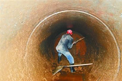 狭小的坑道里，工人正弯着腰挖土。