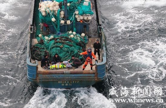 4月21日，空降到渔船上的救生员在指挥直升机调整位置调运中风渔民。曹煜 摄