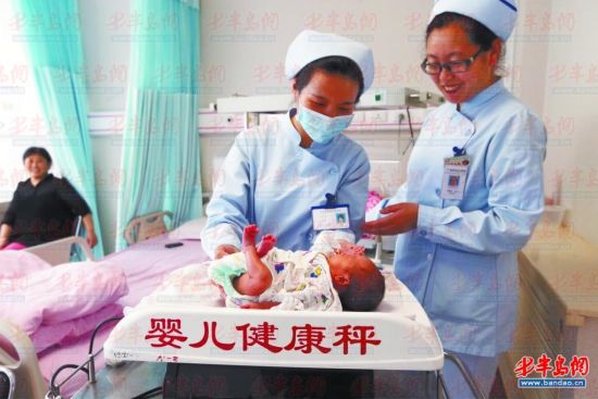在市妇儿医院，护士正在给出生不久的婴儿称体重 。