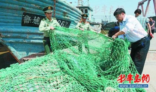 30日，城阳公安边防大队民警在山角渔港码头帮渔民收网具。本报记者 何毅 摄