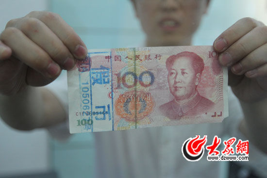 4日银行工作人员展示“C1F9”开头的高仿百元假币。记者 李兆辉 摄