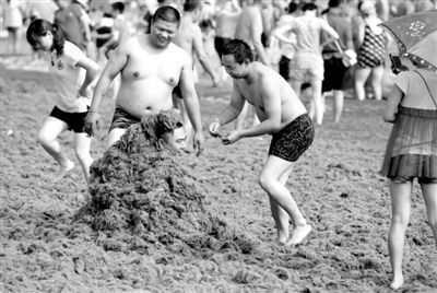 7月3日，山东省青岛市，海滩上游客们在用浒苔玩游戏。 图/CFP