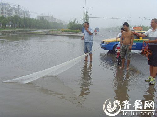路人在有积水的路面上撒网捕鱼