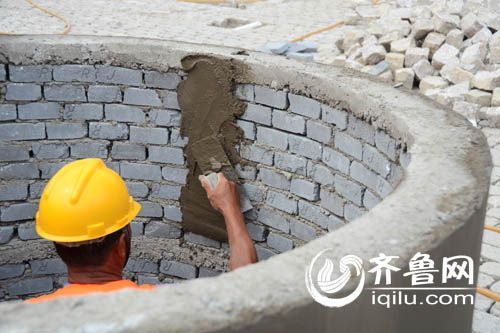 施工现场，一位工人正在给水泥坛内壁抹水泥。（孙志文 摄）
