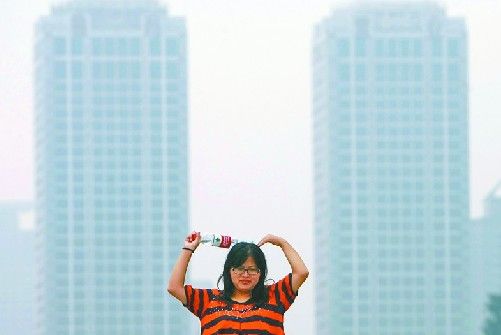 9月22日，一位游客在泉城广场拍照留念，远处的高层建筑被雾霾笼罩。 记者黄中明 摄