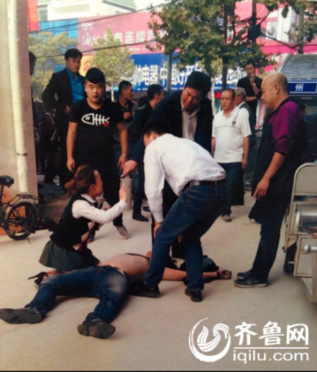网友提供的现场图片，被打商户王某倒在地上，王某的姐姐跪在旁边。