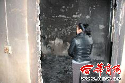 看着自家被烧得残损的楼房，赵女士很无奈 本报记者 曾春 摄