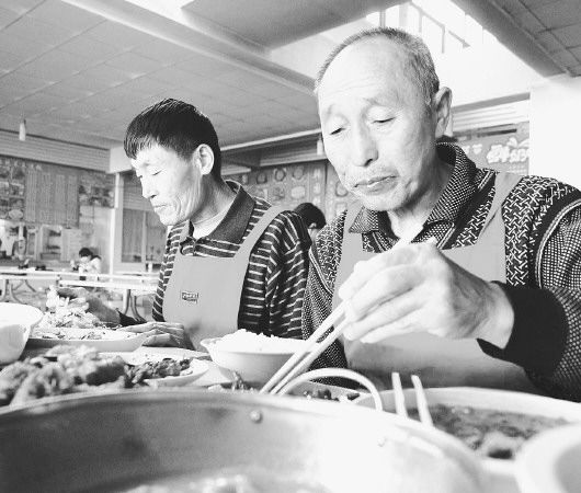 “出了名”之后，吴明华(右)和张明等7名保洁员仍在坚持吃剩饭的传统。 