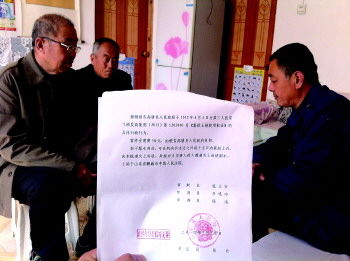 状告县政府的三村民聚在一起讨论判决书。本报记者王尚磊摄