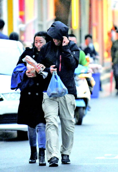 12日,冷空气袭击省城,济南街头许多行人紧缩衣衫。 