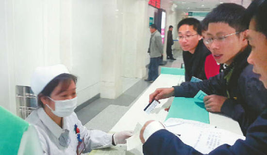 13日，王海林(右一)在齐鲁医院办理挂号手续。 记者 李永明 摄