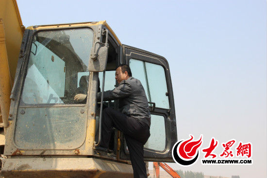 刘冲正攀爬挖掘机，他即将开始一天的工作。自从09年来到垃圾填埋场工作的他，至今已经能够熟练驾驶推土机等多种器械。