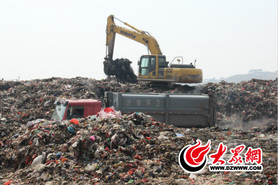 刘冲正驾驶着挖掘机堆放、平整垃圾。